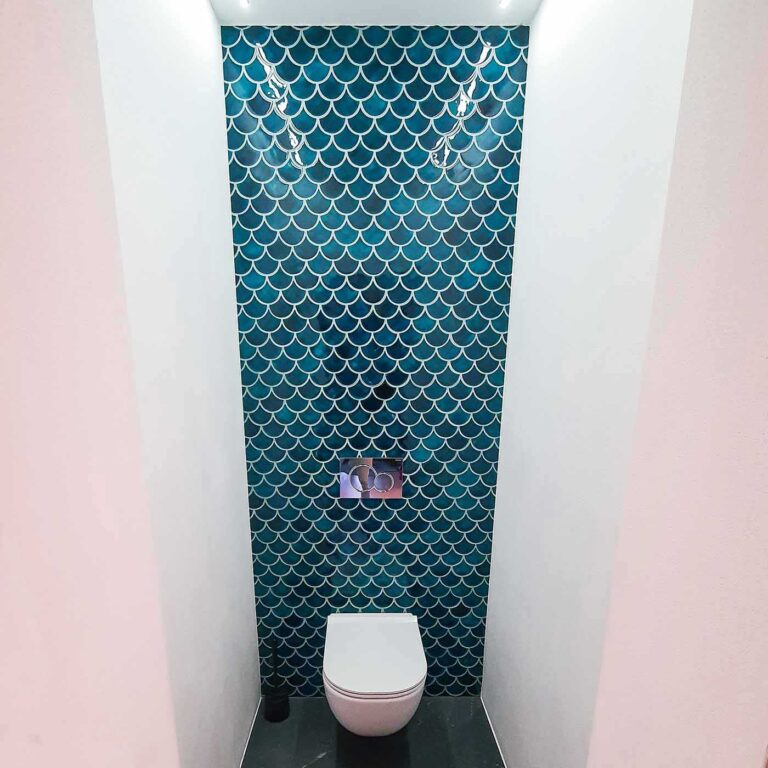 Ceramic mosaic tiles - fish scales, petrol blue color, wall behind the toilet.