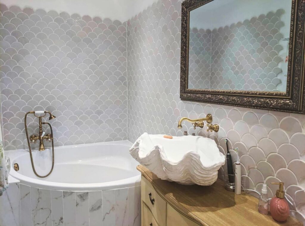 Ceramic mosaic tiles - fish scales, stracciatella color, bathroom wall above the bathtub.