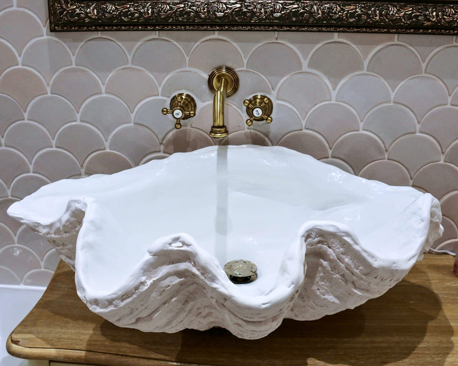 Ceramic mosaic tiles - fish scales, stracciatella color, bathroom wall above the bathtub.