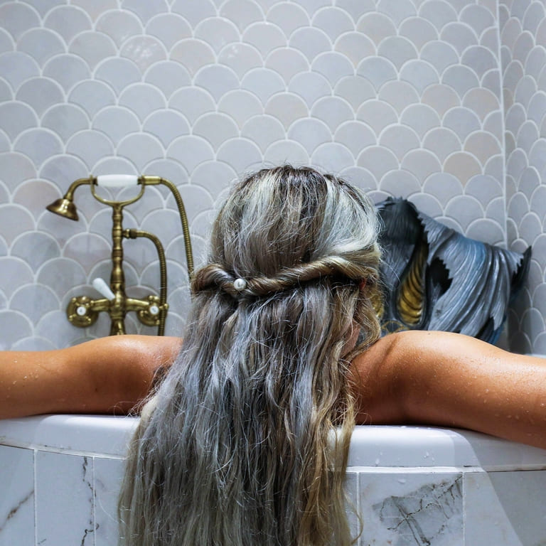 Ceramic mosaic tiles - fish scales, stracciatella color, bathroom wall above the bathtub.